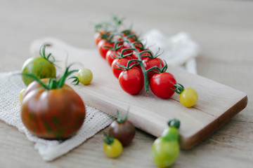 Different variety of tomatoes on wooden background. 