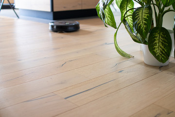 robot vacuum cleaner that moves independently on a house with wooden parquet. Round robot vacuum...