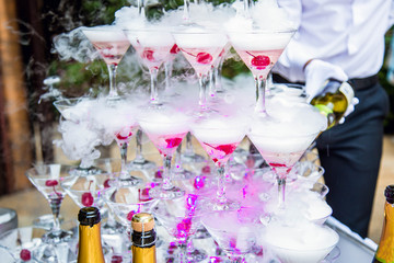 Smoking Beverage Glasses Composition and Barmen. Cups with Smoky Drink on Table Decorated Burning Sparkle Champagne Bottle. Special Decoration Element for Party. Catering Service and Restaurant Party