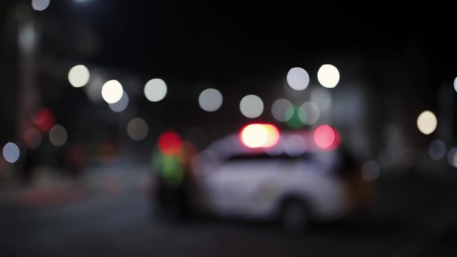 Unfocused shot of police car and officer at night. Road traffic accident concept. Street lamp lights bokeh.