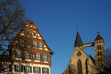 Um Vordergrund ein historisches Fachwerkhaus das ein Museum beherbergt im Hintergrund die Stadtkirche St. Dionys in Esslingen.