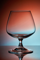 Isolated empty wine glass colorful background. Most wine glasses are stemware, that is they are goblets composed of three parts: the bowl, stem, and foot.