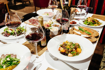served table in the restaurant for a banquet with appetizers, salads and wine