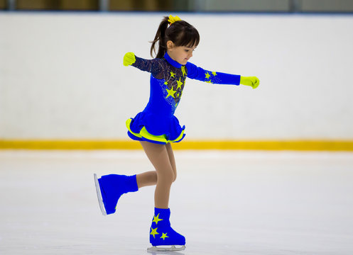 Young Ice Skater Girl In A Dark Blue Dress Doing An Ice Skating Element