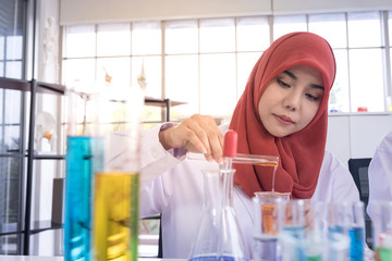 A female muslim scientist in white gown holding test tube in laboratory