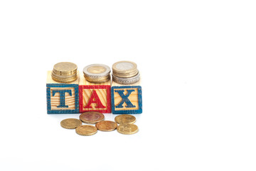 Tax Concept with wooden block on stacked coins,isolated white