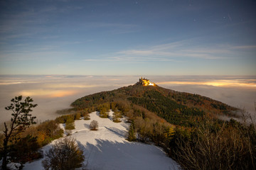 Hohenzollern castle above the clouds fog under a sky full of stars