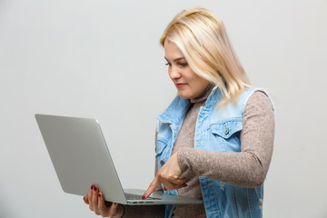 Naklejka premium Portrait of agitated female with long hair holding silver laptop and pointing finger, isolated white background