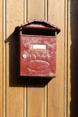 Vintage metallic mailbox on a wooden wall.