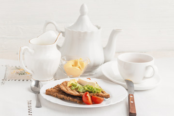 Lunch on a white tea set, toasted bread, cream cheese and lettuce.