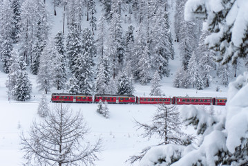 Train rouge circule dans la neige et le blizzard sur un col enneigé dans les grisons en suisse
