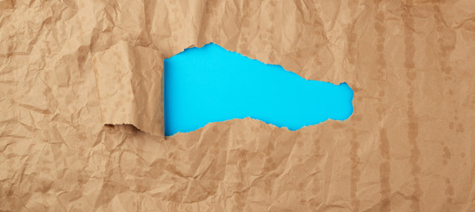 crumpled paper texture from a brown sheet of paper with greasy spots and a large hole with a...