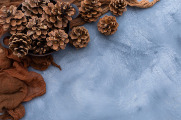 Tabletop scene with brown rag and pine cones on a grey grunge table. Flat layout scene with brown decorative elements. Copy space.