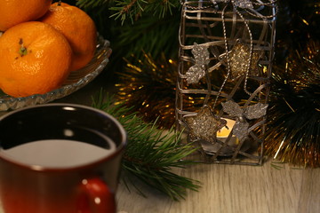 New year's tea. A fragrant candle in a beautiful candlestick illuminates a red Cup of tea, a fir branch and tangerines.