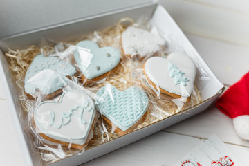 Christmas gingerbread cookies. Hearts and sweaters shapes. Winter sweets on white wooden background. Place for text.