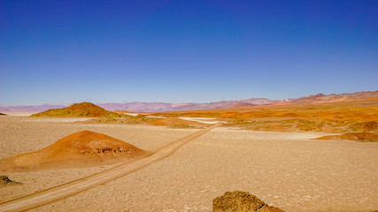Fototapeta na wymiar Road across salt flats in the high altitude desert of Salta's puna region in Argentina