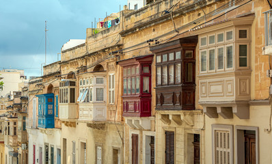 Fototapeta na wymiar Residential house facade with traditional Maltese multicolored enclosed wooden balconies in Sliema, Malta, in summer day. Authentic Maltese urban scene.