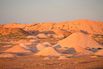 Fototapeta na wymiar Discarded mounds of rock and sandstone mine talings outside outback town of Coober Pedy at sunset