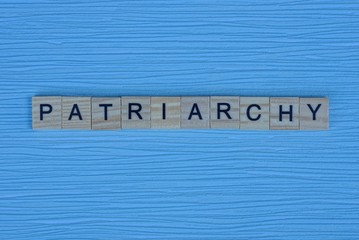 gray word patriarchy from small wooden letters on a blue table