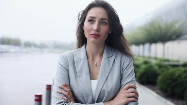 Portrait of Sad and Depressed Woman standing Outside while wind is Blowing. Attractive Woman Looking Unhappy, crossing her Arms, Wearing formal Clothes, Joyless.