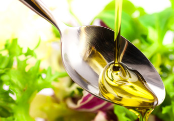 Olive oil being poured into a spoon and salad