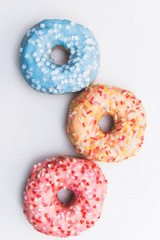 Sweet colored Donuts decorated on a white table. Top view. vertical stock photography.