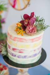 Cake decorated with rose, orchids and succulent. Great desserts surrounded by flowers. Boho style scenery for a sweet table for a celebration, celebration or wedding.