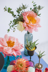 Peonies, eucalyptus, succulents in multi-colored bottles and candlesticks. Great desserts surrounded by flowers. Boho style scenery for a sweet table for a celebration, celebration or wedding.