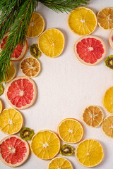 Fototapeta na wymiar Creative holiday Christmas New Year food fruit texture with dried grapefruit, kiwi, orange and lemon with branch of fir tree, top view, empty white background copy space