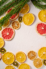 Naklejka na ściany i meble Creative holiday Christmas New Year food fruit texture with dried grapefruit, kiwi, orange and lemon with branch of fir tree, top view, empty white background copy space