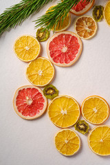 Obraz na płótnie Canvas Creative holiday Christmas New Year food fruit texture with dried grapefruit, kiwi, orange and lemon with branch of fir tree, top view, empty white background copy space
