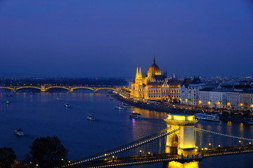 Obraz premium Panoramic view of Budapest at night. Illuminated Hungarian Parliament Building on Danube river and Széchenyi Chain bridge.