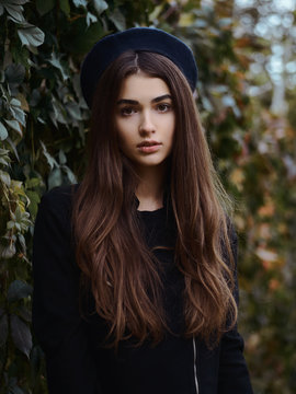 Mood contrasty portrait young elegant french style brown haired woman in beret and black leather jacket enjoying free time strolling in fall city park cinematic stock colour grading ivy background