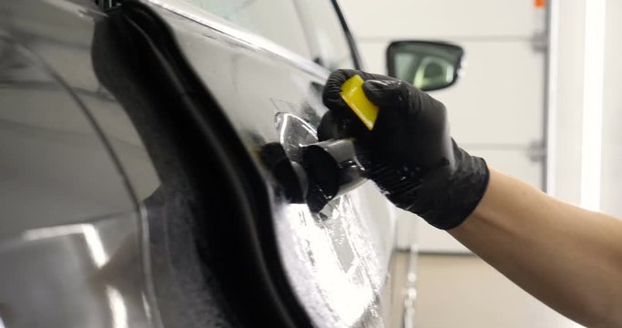 Close up to PPF installation process on a front headlight and hood. PPF is a Paint Protection Film which protect paint from scratches and stone chips. Concept of: Guard, Protect, Car, New, Work.