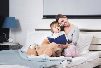 Mother playing with her baby in the bedroom.