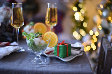 decorated New Year's table or Christmas table  . Closeup of two glasses of champagne in front of burning fireplace