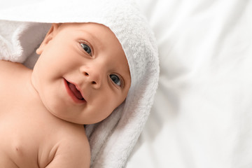 Fototapeta na wymiar Portrait of cute little baby with towel lying on bed