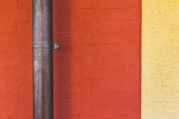 Vintage copper pipe on a red yellow concrete wall background texture