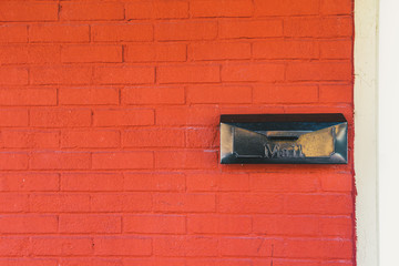 Black mailbox on orange brick wall background texture