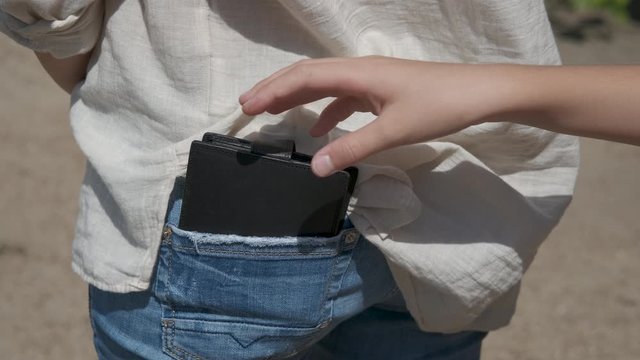 Pocket thief in the street. The wallet is stolen from the back pocket of the trousers.