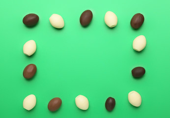 Frame made of chocolate Easter eggs on color background