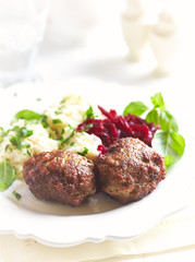 Traditional meatballs with mashed potatoes and fresh herbs. Bright background.