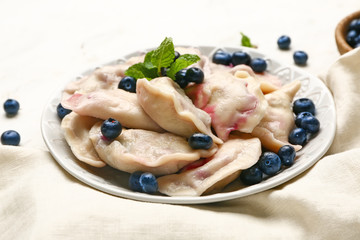 Plate with tasty dumplings and blueberry on table