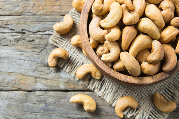 roasted salted raw cashew nuts in wooden bowl on rustic table, healthy vegetarian snack, Anacardium occidentale