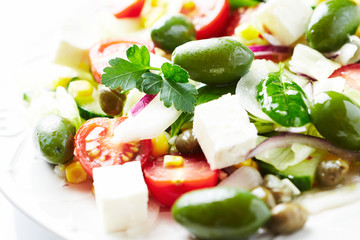  Healthy salad with green olives, feta cheese, sweet corn, cherry tomatoes, red onion, baby spinach, capers and fresh herbs. Close up.