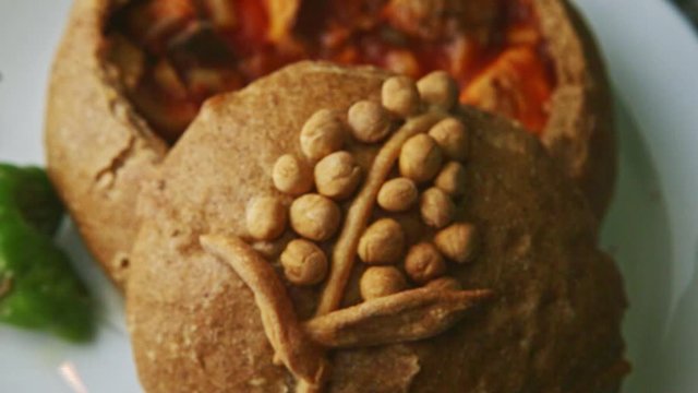 top view closeup exquisite decorated fish soup in brown bread bowl on white plate