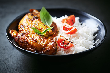 Spicy chicken with rice on black stone background. Close up. 