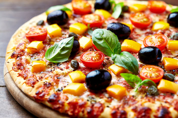 Fototapety  Smaczna pizza z pomidorkami koktajlowymi, serem mozzarella, czarnymi oliwkami, papryką pomarańczową, kaparami i świeżą bazylią. Ścieśniać.