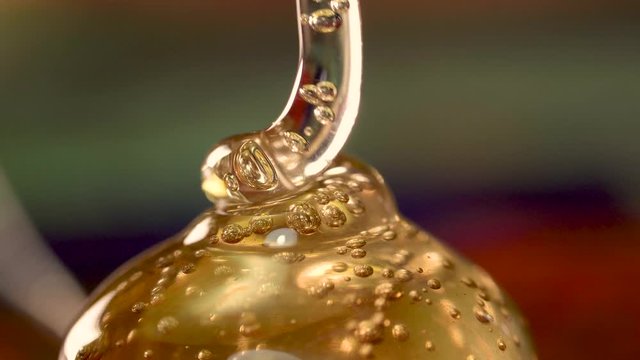 Golden honey being squeezed into pile forming bubbles macro close up detail isolated
