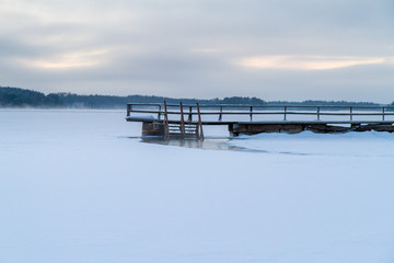 Wonderful winter landscape with snow covered wooden pier, Finland.